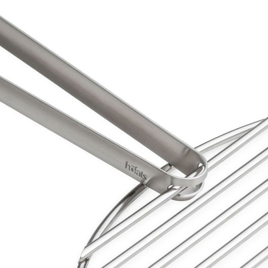 zoom sur le manche de la pince design qui tient sur une grille d'un barbecue