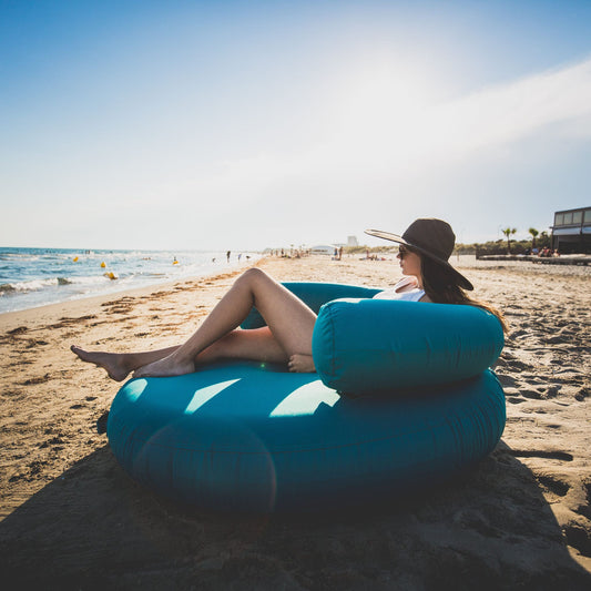 photo du coussin bleu sur la plage  avec une femme allongée dessus